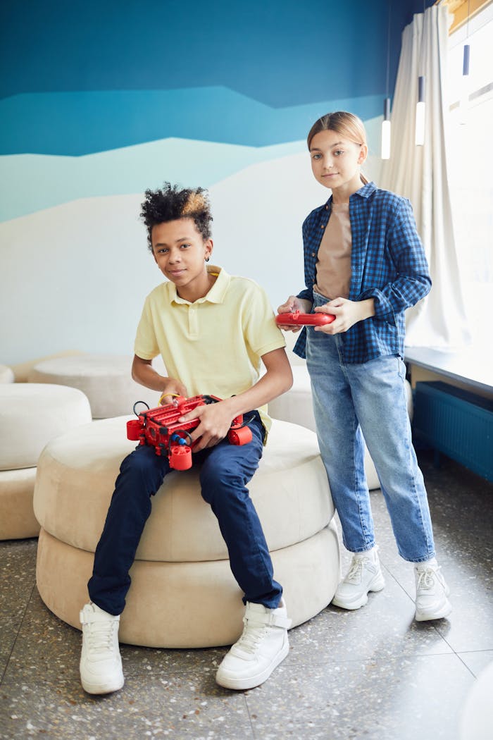Two teenagers learning with a robotic project indoors, smiling and engaged.